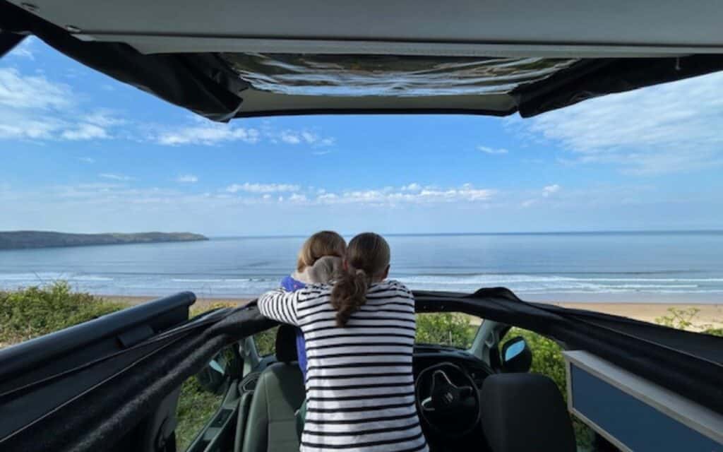 Relaxing beach view seen from inside a vehicle, with two women admiring the ocean.