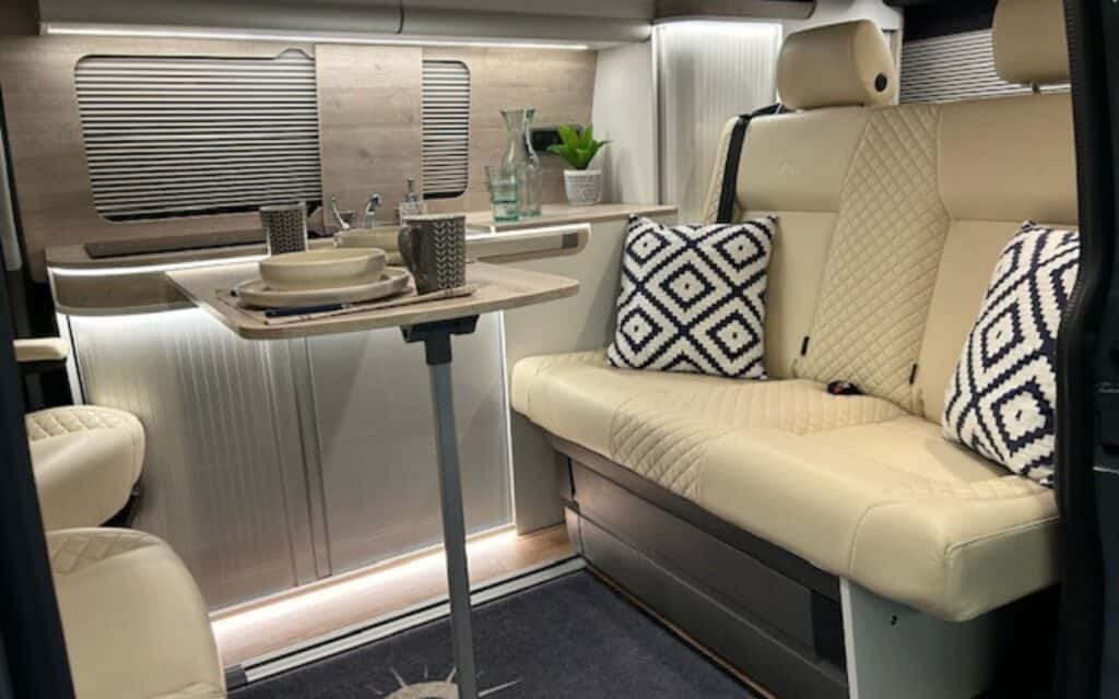 Modern camper van interior with comfortable seating and dining area.