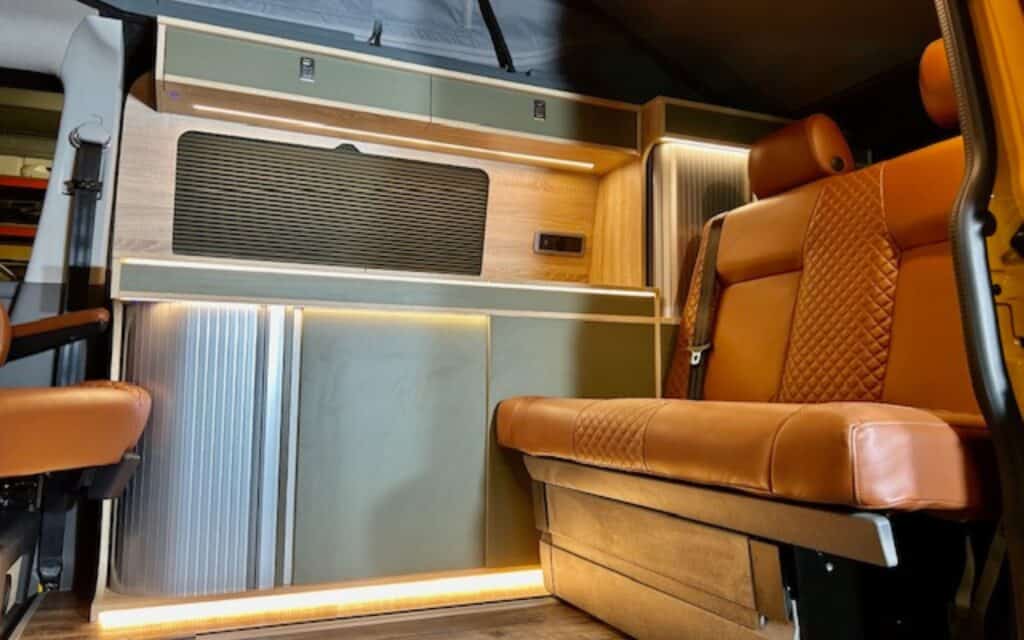 Modern camper van interior with wood accents and leather seating.