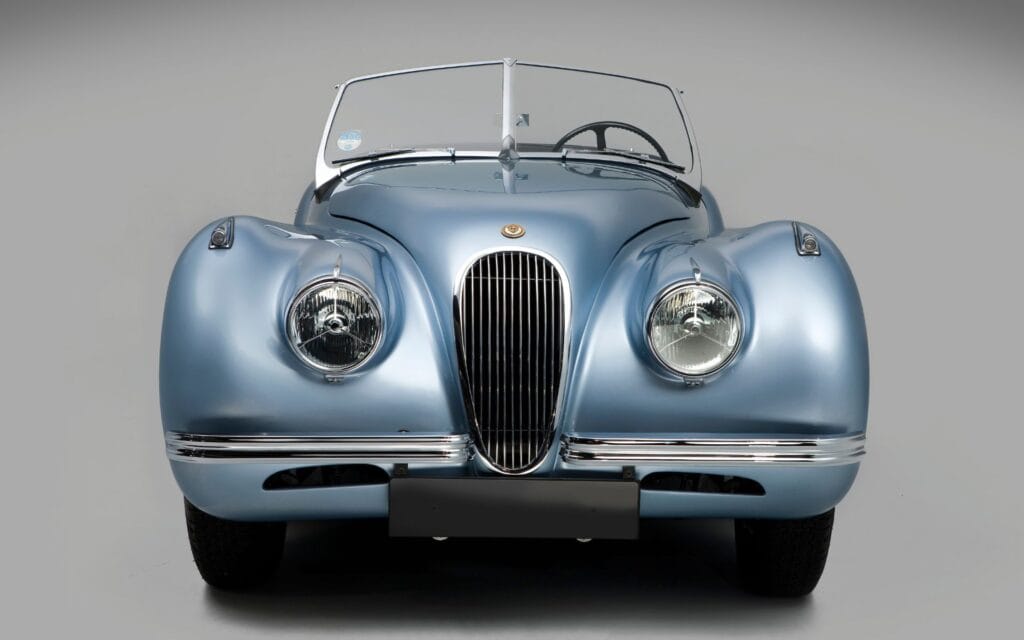 Front view of a restored vintage blue car with sleek design and chrome details.