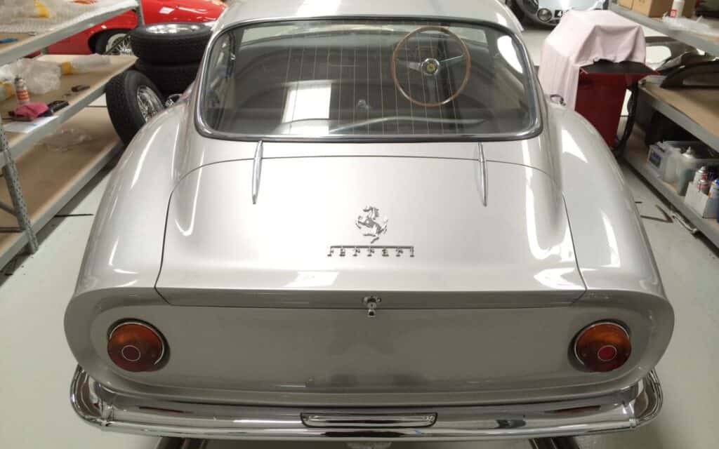 A sleek silver Ferrari 250 GTO with round taillights and vintage design.